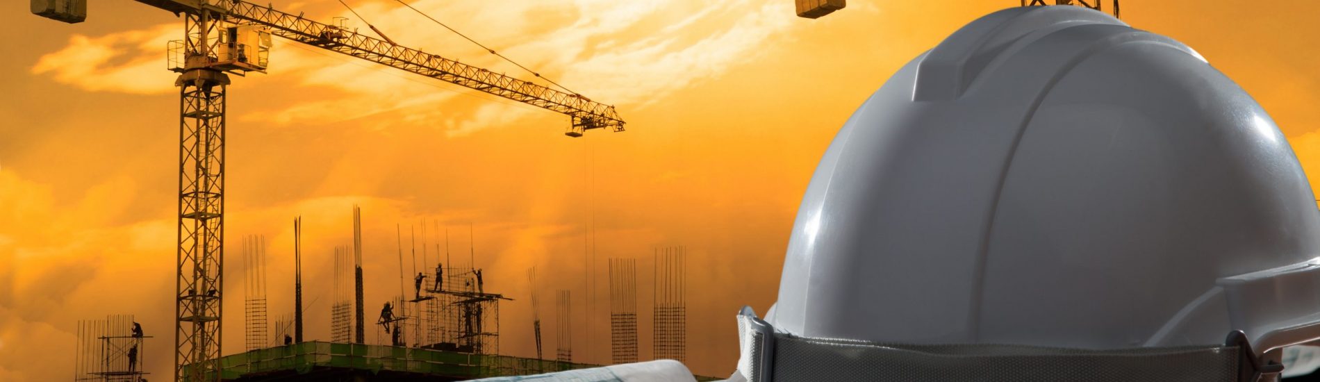 file of safety helmet and architect pland on wood table with sunset scene and building construction